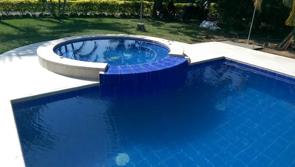 Round raised spa with deep blue tile spilling into a deep blue pool