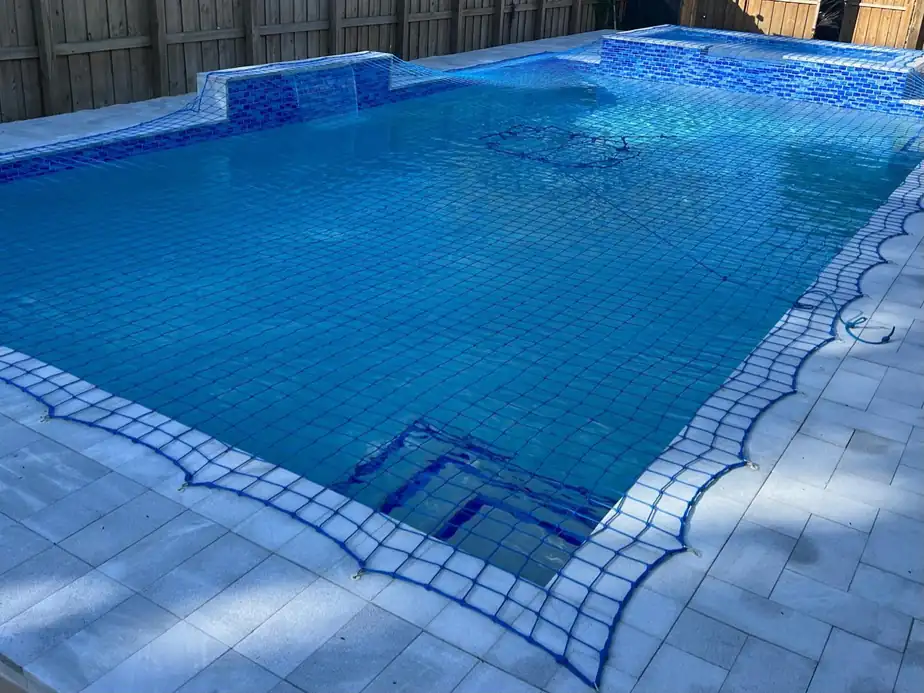 Tiled pool with a spa scupper spilling into it, safety net over the water